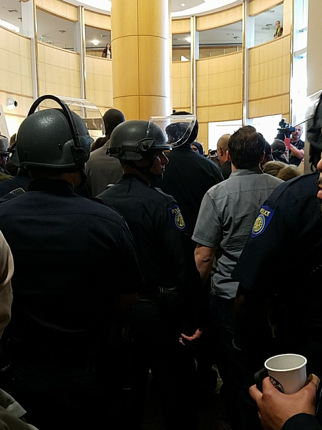 Police in riot gear stand guard in the foyer of Sacramento, Calif., City Hall on March 27, 2018.